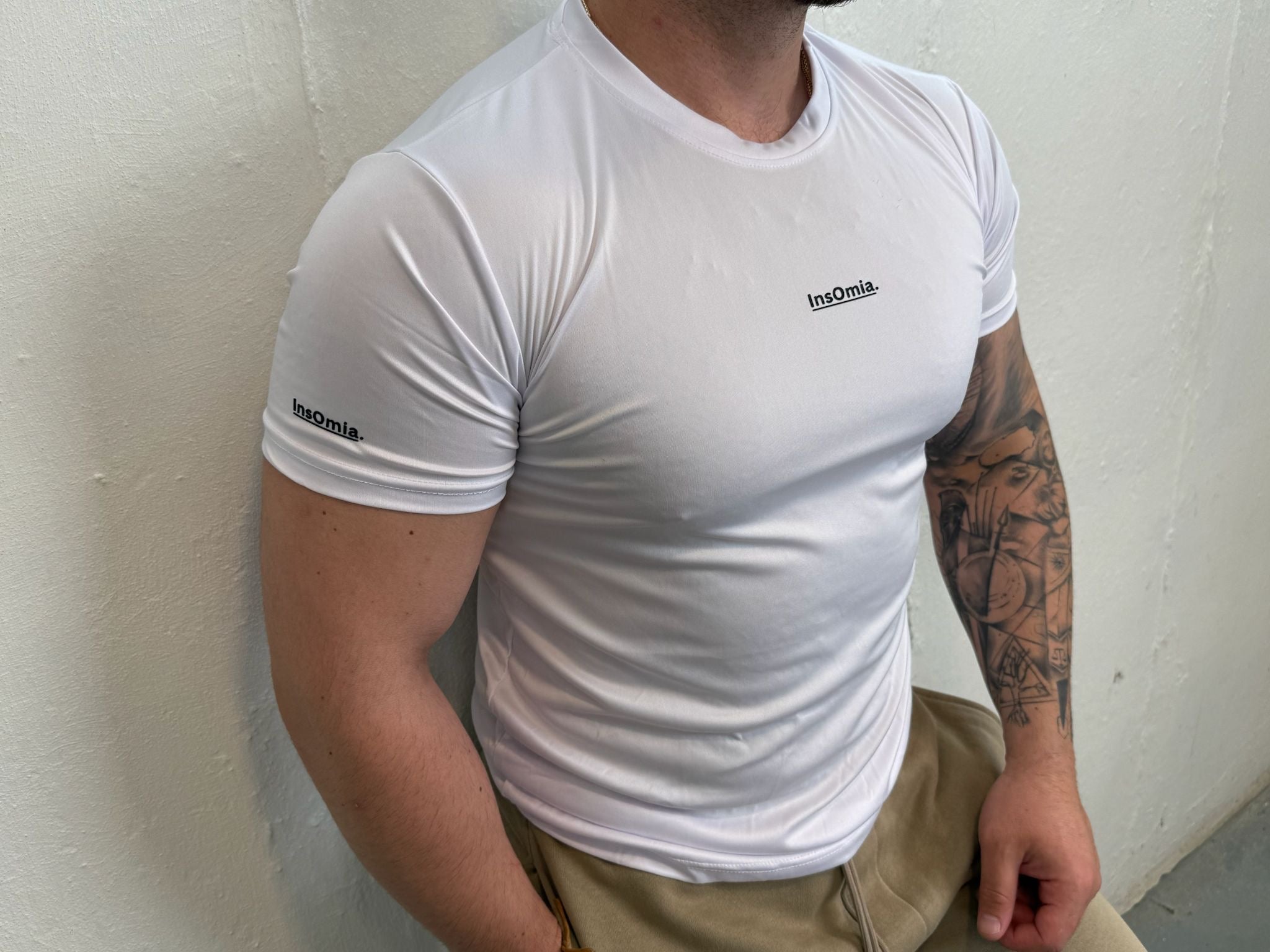 Person wearing a white t-shirt with a logo on a plain background